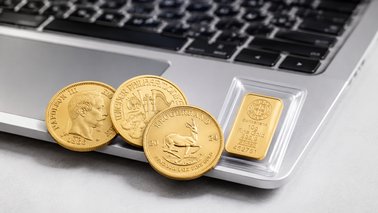Une sélection de lingotins et de pièces d'or d'investissement posée sur un clavier d'ordinateur portable, symbolisant l'achat en ligne.